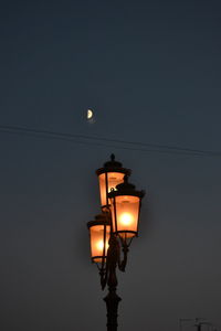 Low angle view of illuminated street light against sky