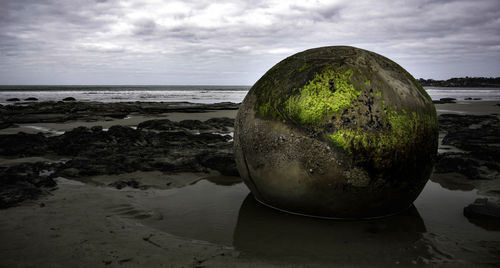 Scenic view of rocks on beach against sky