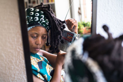 Woman holding equipment reflecting on mirror at home