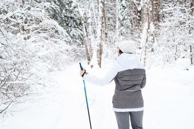 Rear view of woman skiing on snow covered landscape