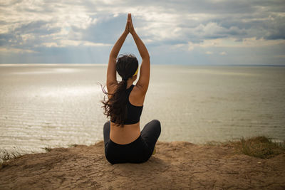 Yoga woman on top of rock near sea