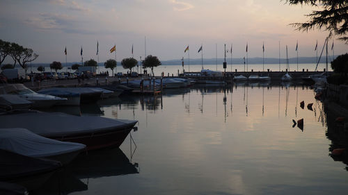 Boats moored at harbor against sky during sunset