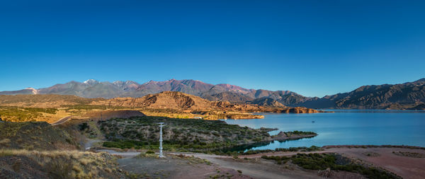 Scenic view of sea and mountains against clear blue sky