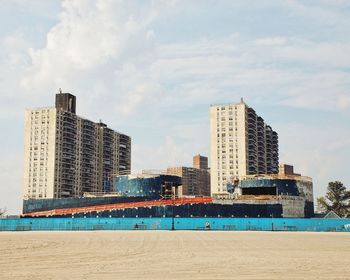 City at waterfront against cloudy sky