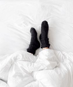 Low section of person wearing socks while lying down on bed
