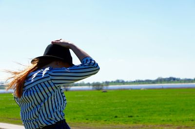 Side view of woman standing on field against clear sky