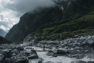 A hiker crossing beas river on rainy day