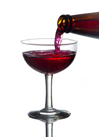 Close-up of wineglass on glass against white background