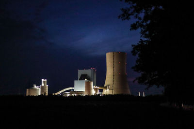 Low angle view of factory against sky at night