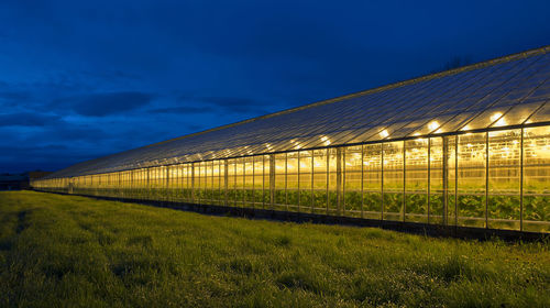 View of greenhouse and agricultural field against sky at night
