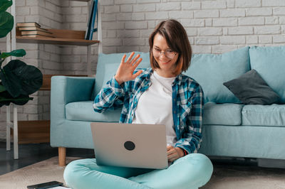 Woman using phone while sitting on sofa