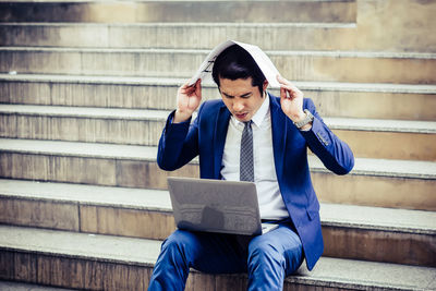 Businessman using laptop while sitting on steps