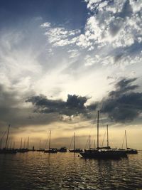 Silhouette boats sailing in sea against sky during sunset