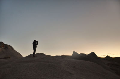 Silhouette man standing on mountain against sky during sunset