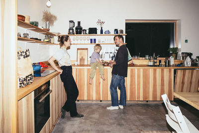 Father and mother talking while preparing food with son in kitchen at home