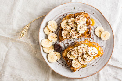 Ready to eat bruschettas with honey, banana and chocolate on a plate on the table. 