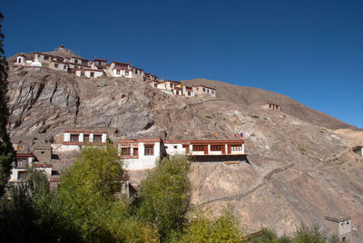 Low angle view of house and mountains against clear blue sky