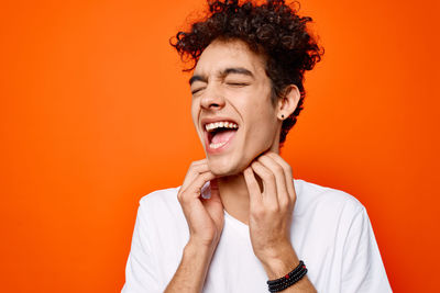 Portrait of smiling young woman against orange background