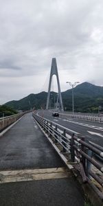 View of suspension bridge against cloudy sky