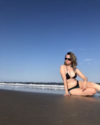 Young woman on beach against sky