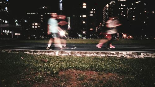 People playing on illuminated street at night