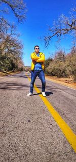 Full length portrait of man standing on road against sky