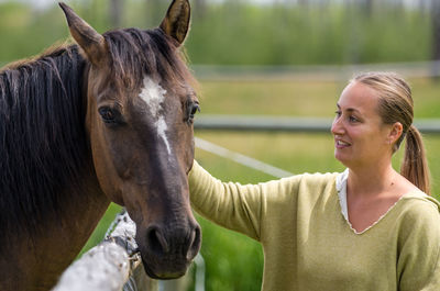 Smiling woman touching horse