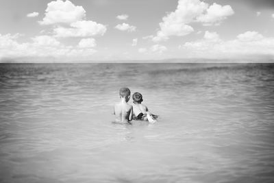 Couple swimming in sea against sky