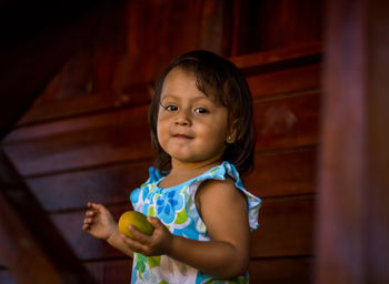 Portrait of cute girl holding curtain at home