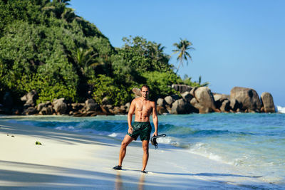 Portrait of shirtless man standing on shore at beach