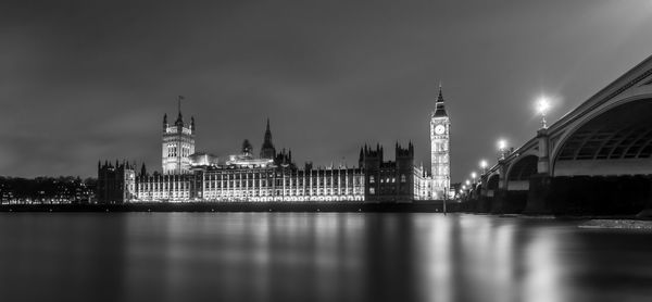 Illuminated city by river at night