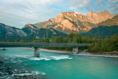 Bridge over river by mountains against sky