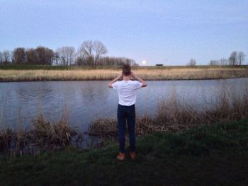 Rear view of boy standing in lake against clear sky