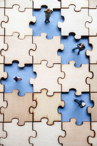 High angle view of figurines amidst wooden jigsaw puzzle