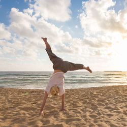 Full length of man skateboarding on beach against sky