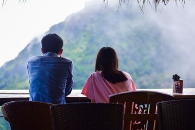 Couple sitting on chair against mountain