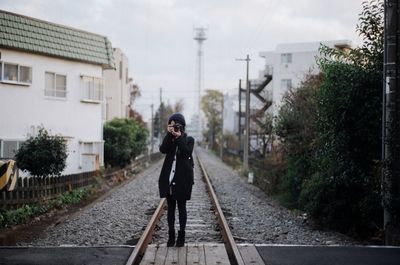 Man walking on railroad track against sky