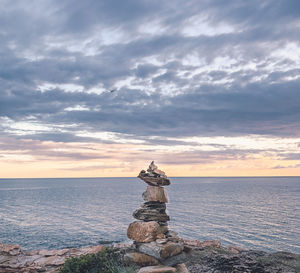 Stack of rock on sea against sky during sunset