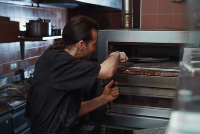 Male chef preparing pizza in italian restaurant kitchen