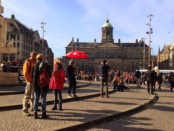 Crowd at dam square with royal palace of amsterdam against sky