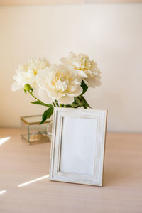 Portrait white picture frame mockup on wooden table.