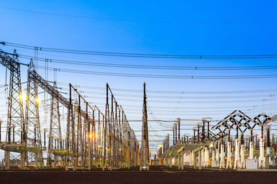 Electricity pylons against clear blue sky