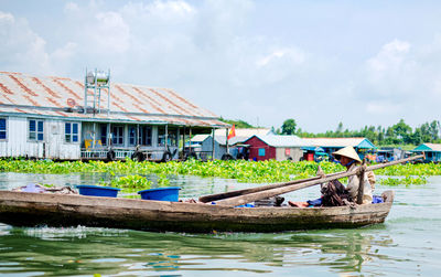 Boats moored in river by buildings against sky