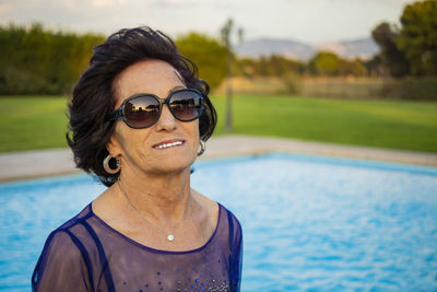 Portrait of smiling woman standing by swimming pool