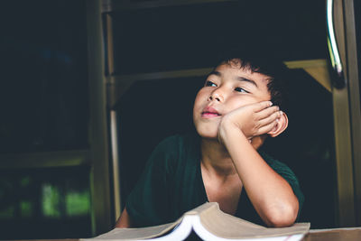 Portrait of boy looking away while sitting on table