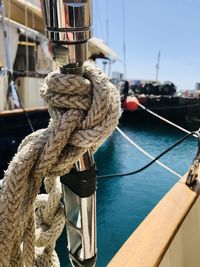 Close-up of rope tied on wooden post in sea