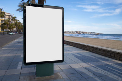 Empty road by sea against sky in city