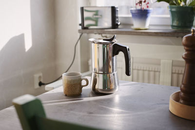 Coffee maker and cup on table