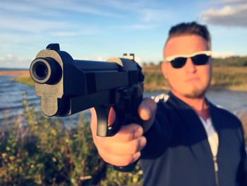 Man holding gun by lake