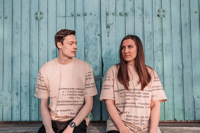 Portrait of young couple standing against wall